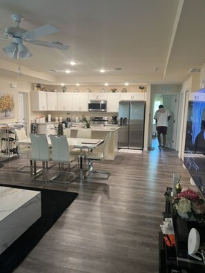 A modern kitchen with white cabinets, stainless steel appliances, and a dining area with a glass table and chairs. - Relaxing Port LaBelle Retreat / Spacious Home Near Nature & Golf (Port LaBelle)