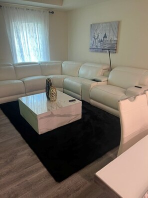 A modern living room with a sectional sofa, a coffee table, and a painting on the wall. - Relaxing Port LaBelle Retreat / Spacious Home Near Nature & Golf (Port LaBelle)