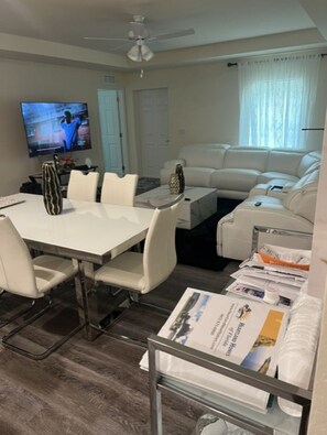 A living room with a white sofa, a dining table with chairs, a TV, and a ceiling fan. - Relaxing Port LaBelle Retreat / Spacious Home Near Nature & Golf (Port LaBelle)