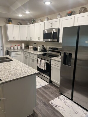 A modern kitchen with white cabinets, stainless steel appliances, granite countertops, and a marble backsplash. - Relaxing Port LaBelle Retreat / Spacious Home Near Nature & Golf (Port LaBelle)