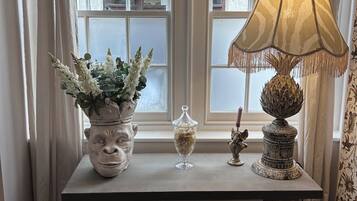 A room with a table featuring a potted plant, a glass container, and a decorative lamp.