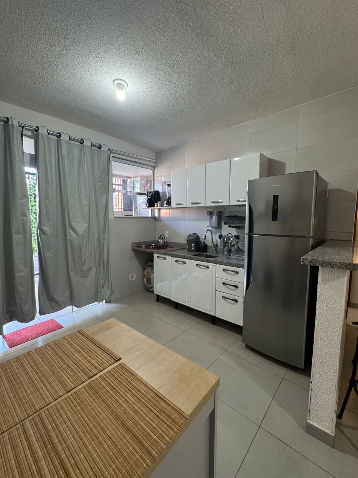 Una cocina moderna con armarios blancos, un refrigerador de acero inoxidable y una mesa de madera.