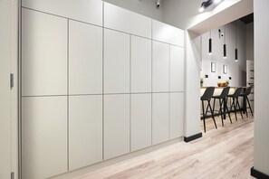 Une cuisine moderne dotée d’un ensemble de meubles blancs intégrés, d’un plan de travail en bois et d’un coin repas avec des chaises noires.