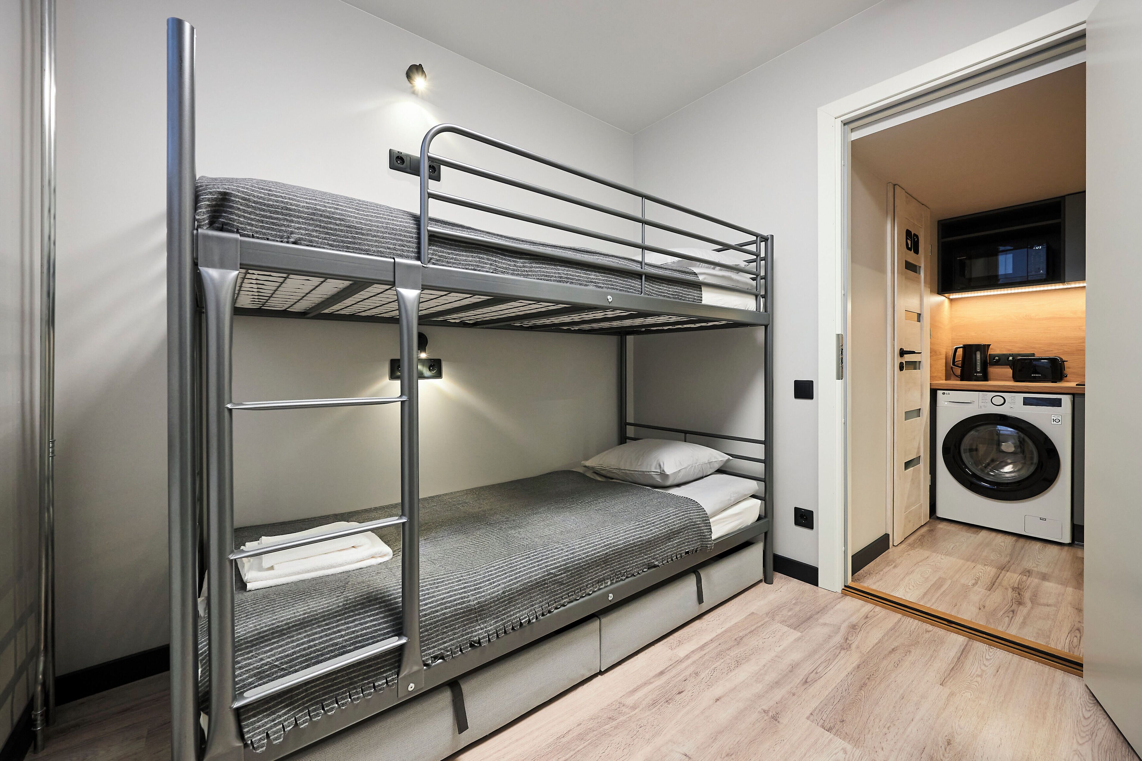 A bunk bed with a washing machine in the adjacent room.