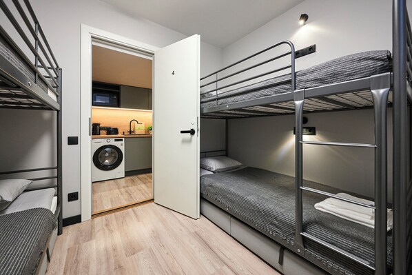Une chambre d’hôtel compacte avec des lits superposés, un lave-linge et une kitchenette.