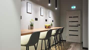 A modern interior with a long wooden table, four grey chairs, and framed pictures on the wall.