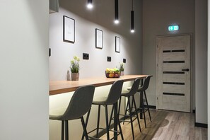 A modern interior with a long wooden table, four grey chairs, and framed pictures on the wall.