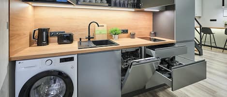 A compact kitchen with a built-in washing machine, a toaster, and a sink with a faucet.