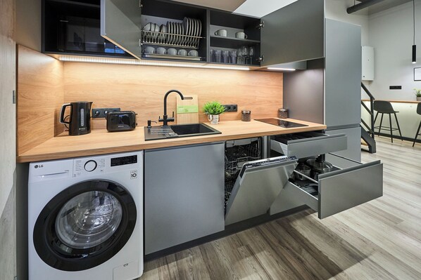 A compact kitchen with a built-in washing machine, a toaster, and a sink with a faucet.