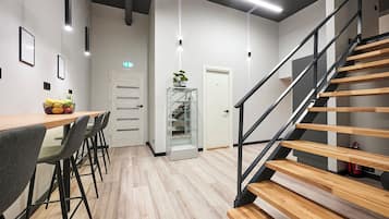 Un interior moderno con una escalera de madera, una zona de comedor con sillas, un expositor de vidrio y una puerta marcada con el número 3.