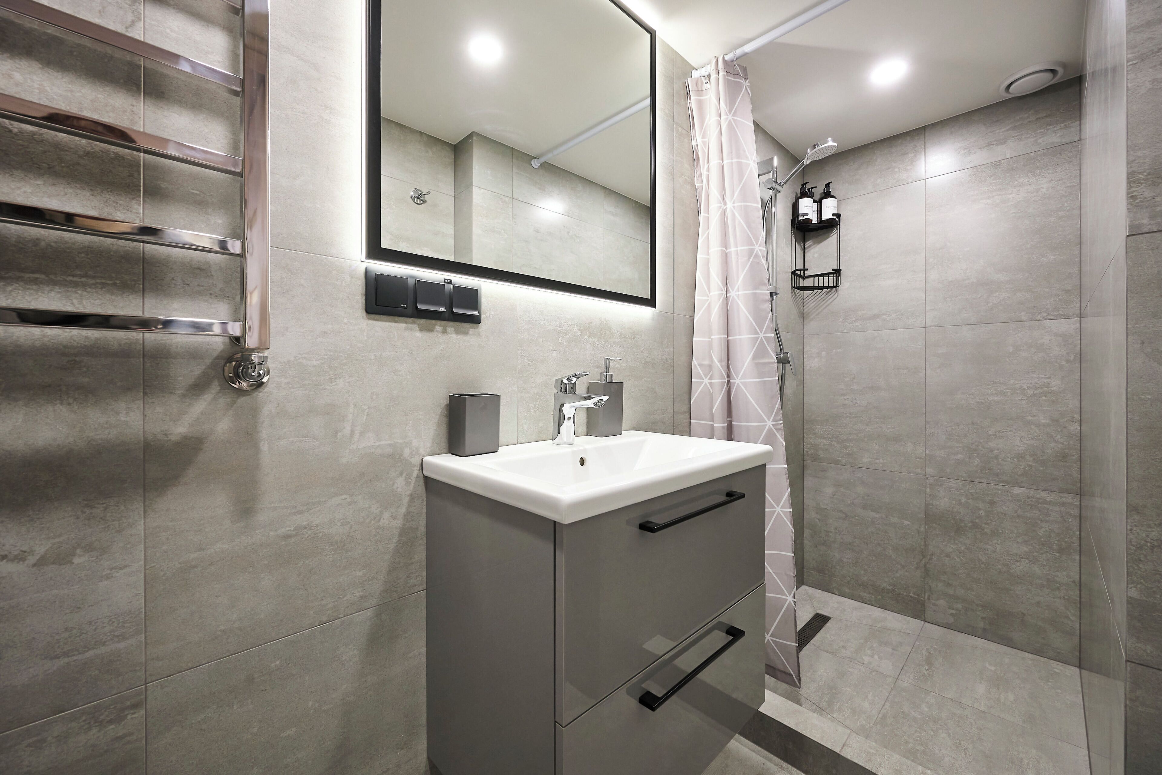 Un baño moderno con lavamanos integrado, espejo y ducha.
