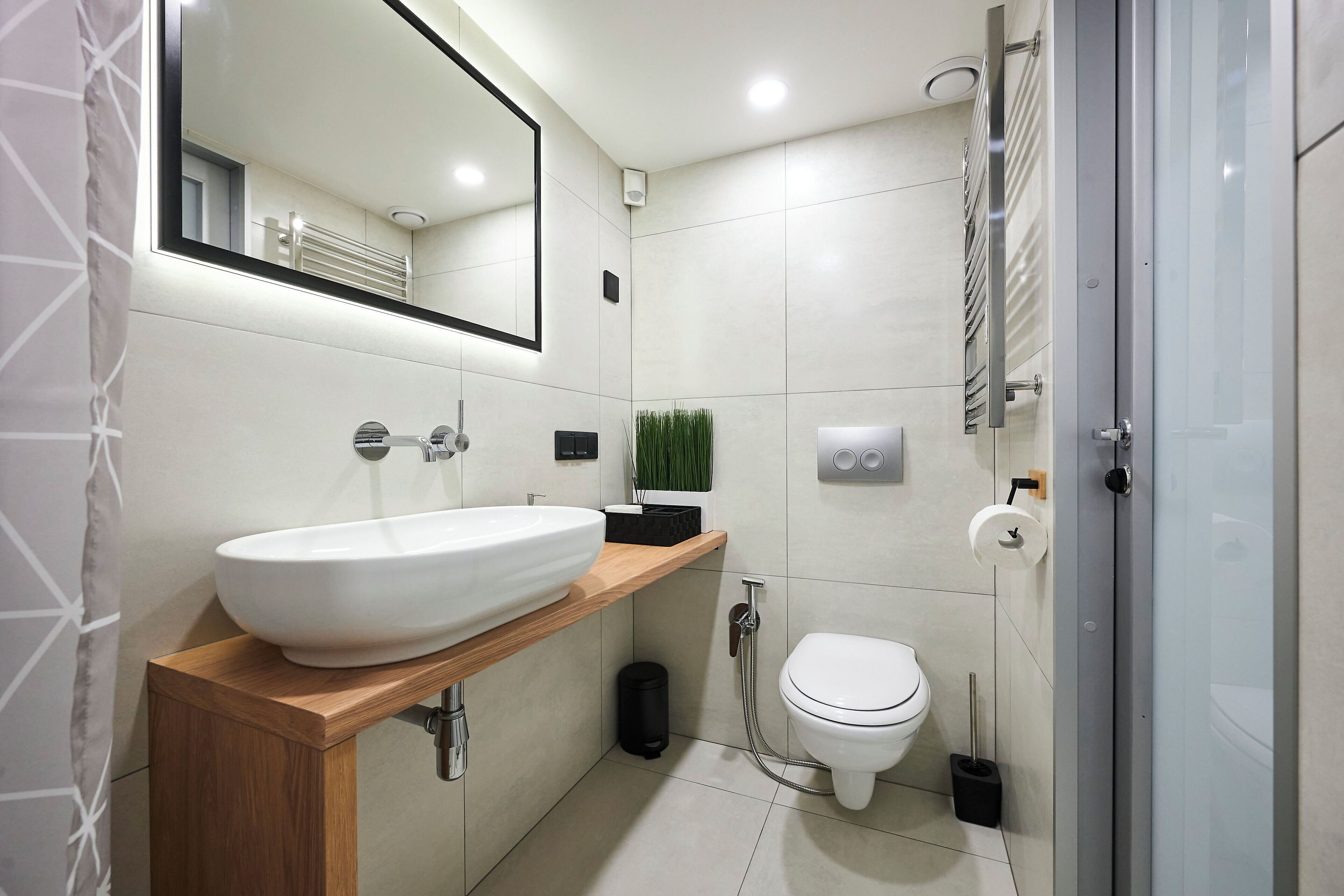 Un baño moderno con un lavamanos grande de color blanco, un inodoro y una zona de ducha.