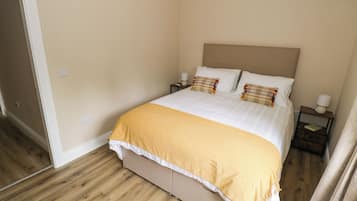 A bedroom with a bed, nightstands, a lamp, and a door.