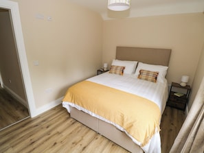 A bedroom with a bed, nightstands, a lamp, and a door.