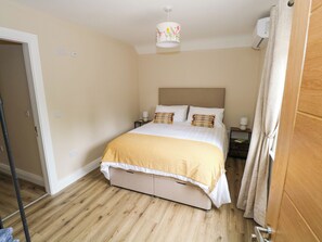 A bedroom with a bed, bedside tables, a lamp, a ceiling light, and a door.