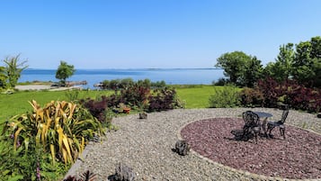 A garden with a circular seating area, a gravel path, and a view of the sea.