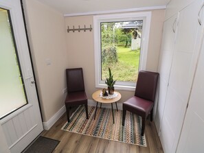 A small room with two chairs, a table with a plant, and a window with a view of a garden.