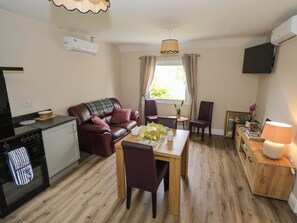 A compact living space with a kitchenette, a dining area, a sofa, and a television mounted on the wall.