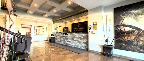 A hotel reception area with a stone counter, a large framed artwork, and a modern ceiling design.