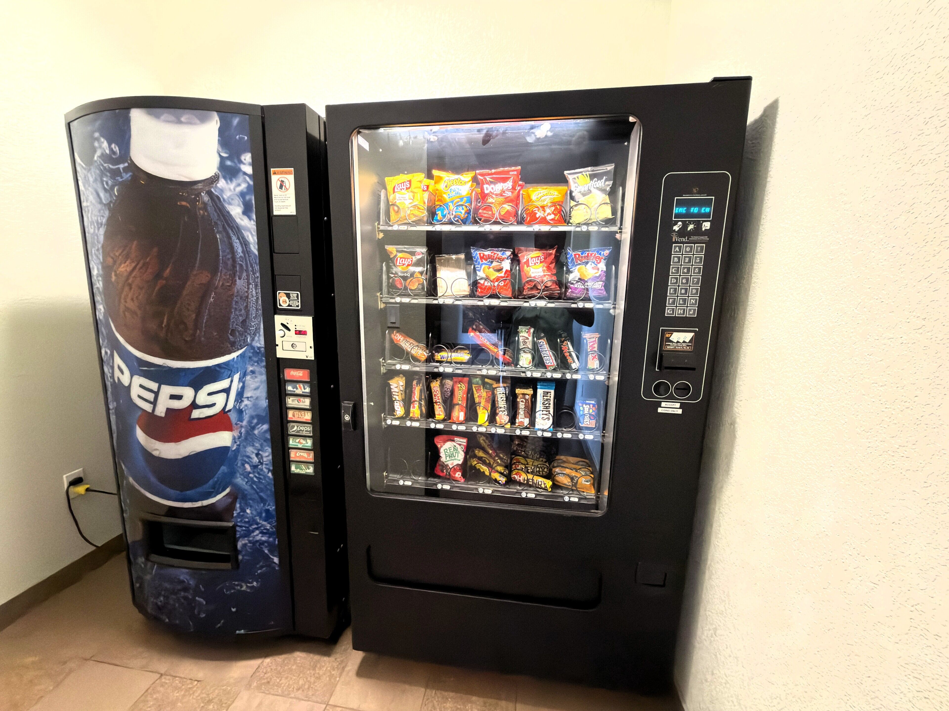 To salgsautomater, hvoraf den ene er mærket med Pepsi og den anden indeholder forskelligt snacks.