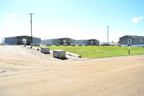 A row of single-story mobile homes with a dirt road in the foreground.