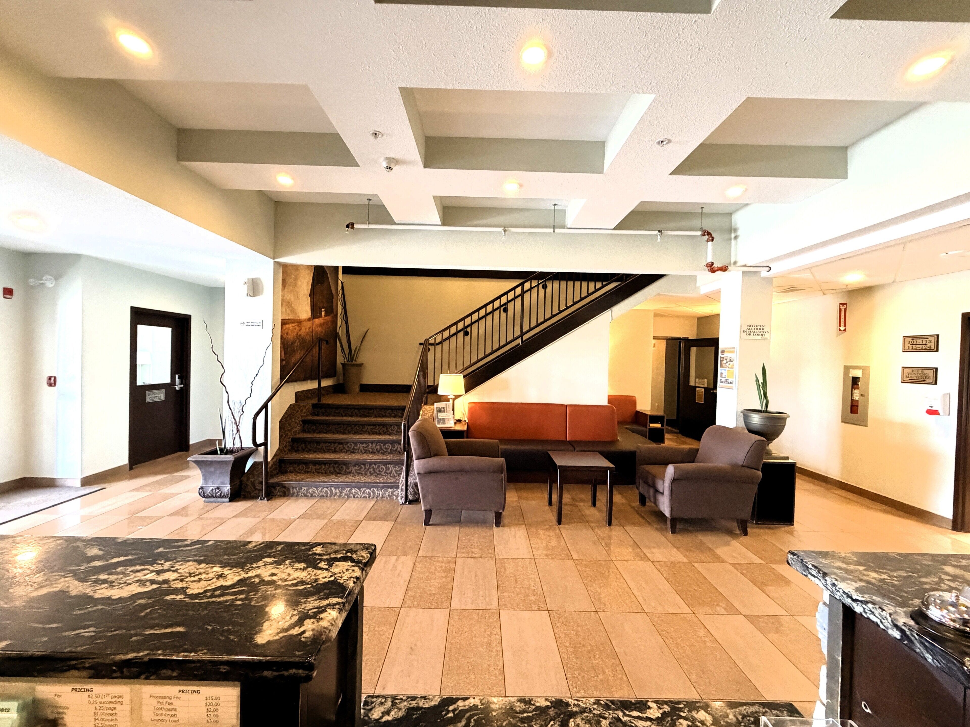 A lobby with a staircase, seating area, and reception desk.