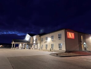 A hotel with a prominent 'INN' sign, a covered entrance, and a parking lot. - Golden Prairie Hotel & Lodge (Consort)