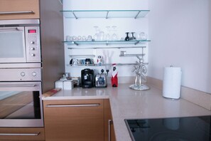 Eine Küche mit Edelstahlgeräten, einer Kaffeemaschine, einem Toaster und Glastablaren mit Küchenutensilien.