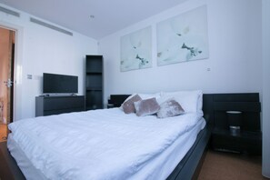 Ein Schlafzimmer mit Bett, Fernseher, Kleiderschrank und Bildern an der Wand.