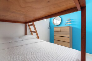 A bedroom with a wooden bed frame, a white mattress, a wooden dresser, and a blue wall. - Azul | Pool View, 5-Minute Walk to the Beach (Playa Juan Dolio)