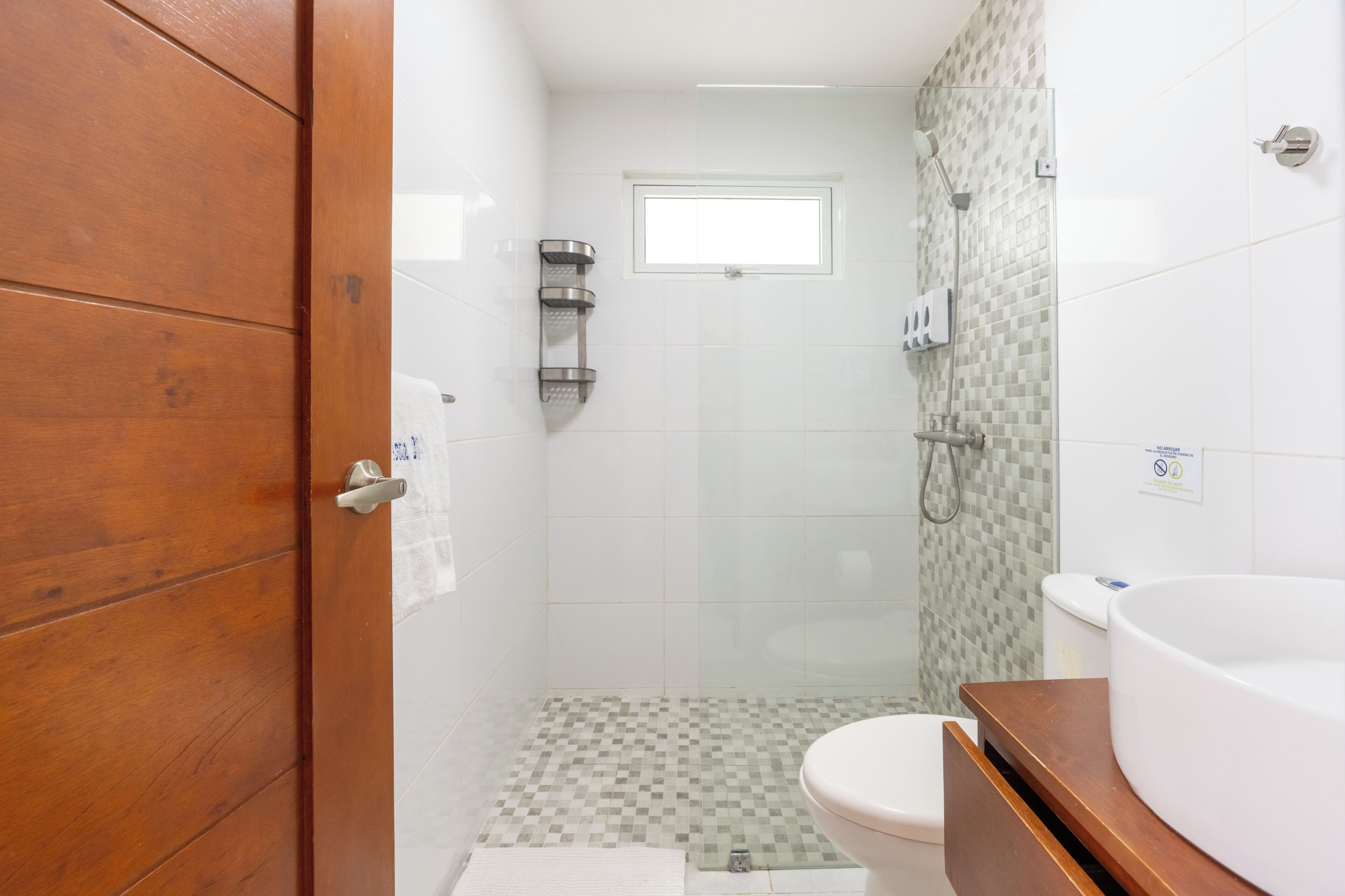 A bathroom with a wooden door, a toilet, a shower, and a large bathtub.