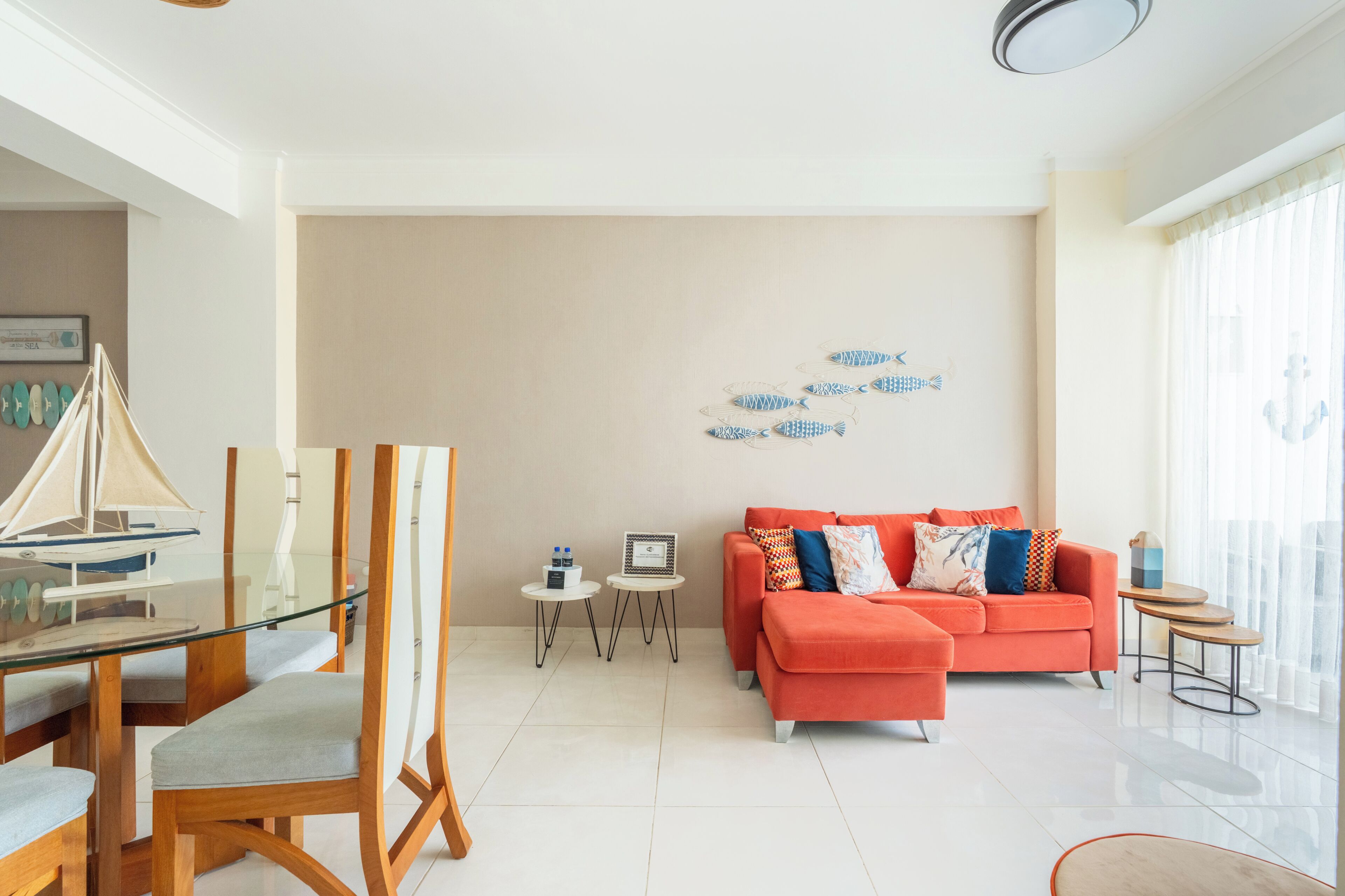 A modern living room with a glass dining table, a sofa, and a wall art piece.
