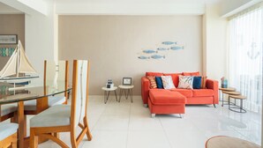 Una sala de estar moderna con una mesa de comedor de vidrio, un sofá y una obra de arte en la pared.