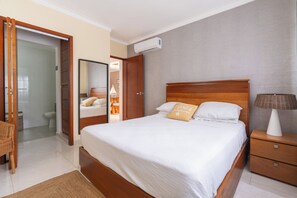 Ein Hotelzimmer mit Bett, Nachttisch, Lampe und Blick ins Badezimmer.