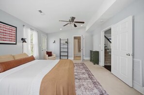 Een slaapkamer met een bed, een stoel, een trap, een dressoir en een wenteltrap.