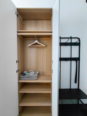 Ein Kleiderschrank mit mehreren Einlegeböden, einer Kleiderstange und einem schwarzen Metallgestell.
