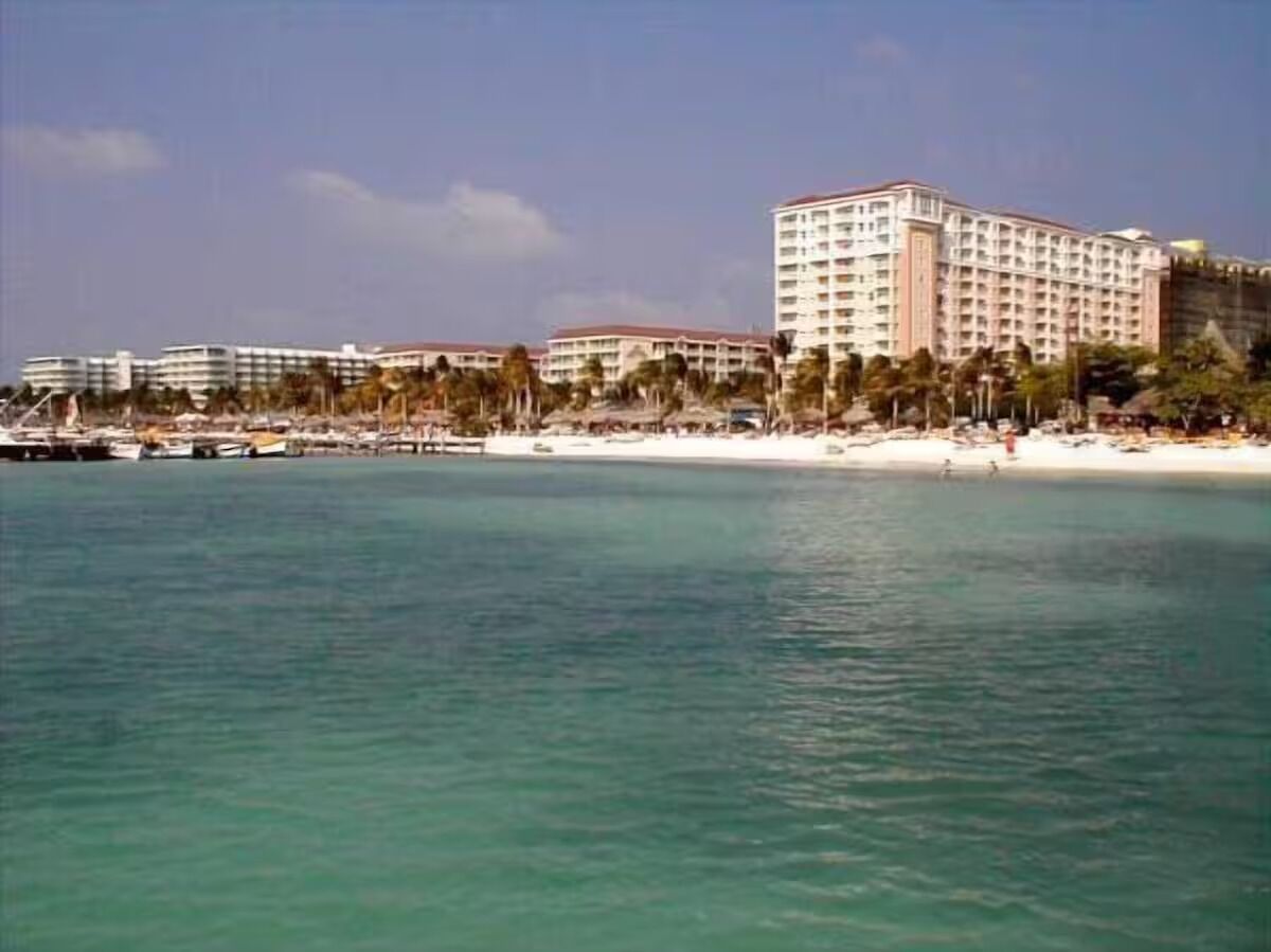 A coastal hotel with multiple buildings, a beach, and clear turquoise water.