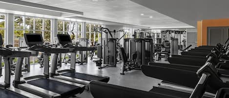 Un gimnasio con cintas de correr, máquinas de pesas y equipo de ejercicio.