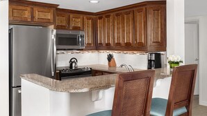 A kitchen with wooden cabinets, stainless steel appliances, a granite countertop, and a sink. - OCEANFRONT- Beautiful 2 Bedroom-Marriott's Aruba Surf Club - Full Resort Access (Noord)