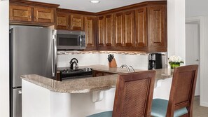 Una cocina con armarios de madera, electrodomésticos de acero inoxidable, encimera de granito y un lavabo.