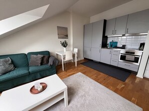 Ett kompakt bostadsutrymme med en soffa, ett soffbord, ett matbord och ett litet kök.