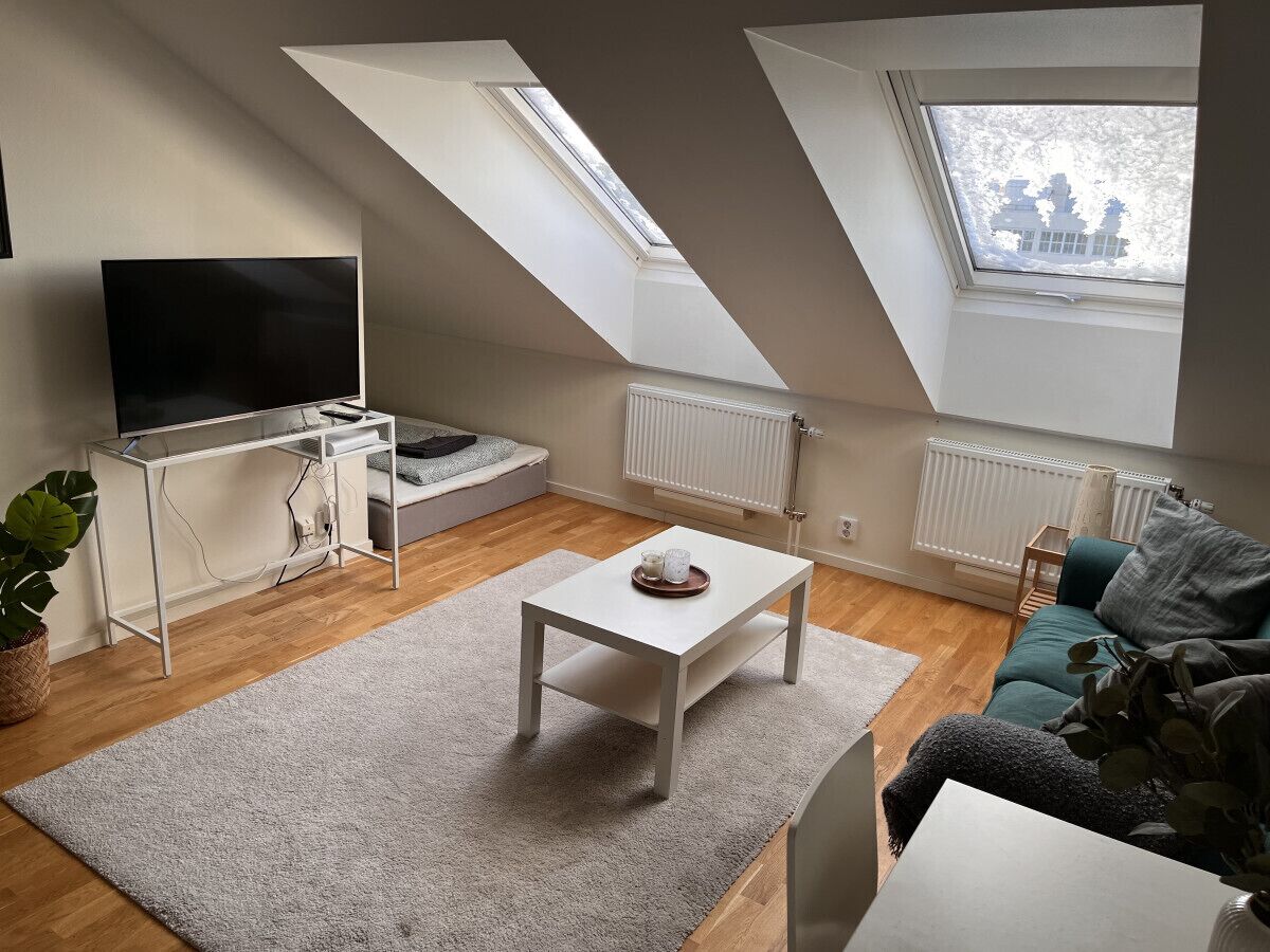 Ett modernt vardagsrum med en TV, ett vitt soffbord och en soffa.