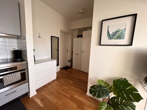 Ett modernt kök med vita skåp, en ugn i rostfritt stål och en kaffebryggare.