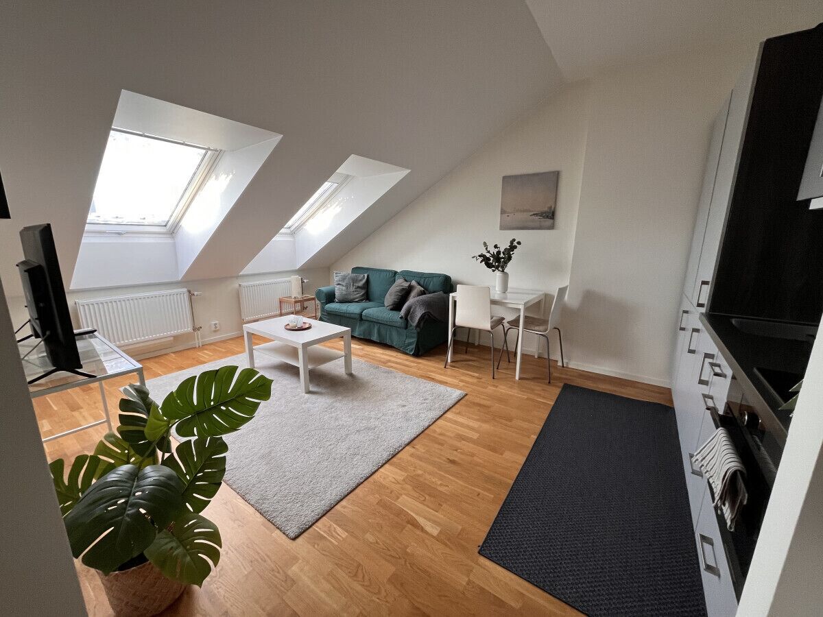Un appartement moderne comprenant une chambre en mezzanine, un espace de vie avec un canapé et une table basse, un coin repas et une cuisine.