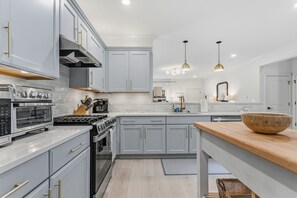 A modern kitchen with grey cabinets, stainless steel appliances, and pendant lighting. - South Haven Retreat • Indoor/Outdoor Pool • Beach (South Haven)