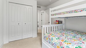 A room with a bunk bed, a white wardrobe, and a door leading to another room. - South Haven Retreat • Indoor/Outdoor Pool • Beach (South Haven)