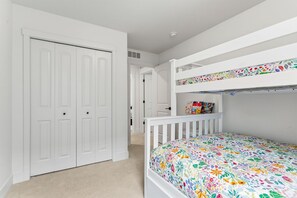 Ein Zimmer mit einem Etagenbett, einem weißen Schrank und einer Tür zu einem anderen Raum.