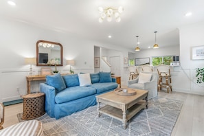Ein modernes Wohnzimmer mit einem blauen Sofa, einem Couchtisch und einem Essbereich mit Stühlen.