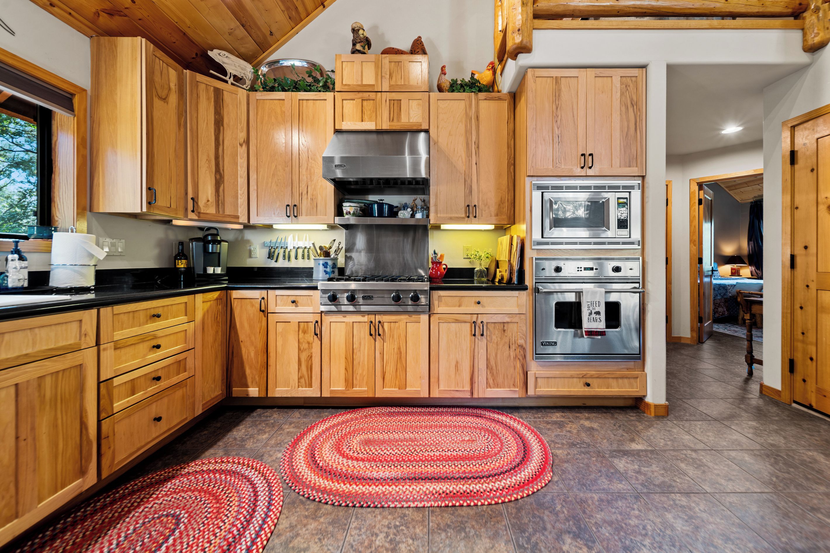 A modern kitchen with wooden cabinets, a gas stove, an oven, and a microwave.