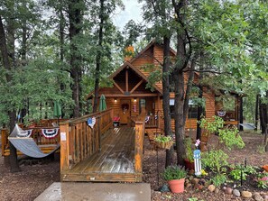 Eine Holzhütte mit Veranda, umgeben von Bäumen und einem Garten.